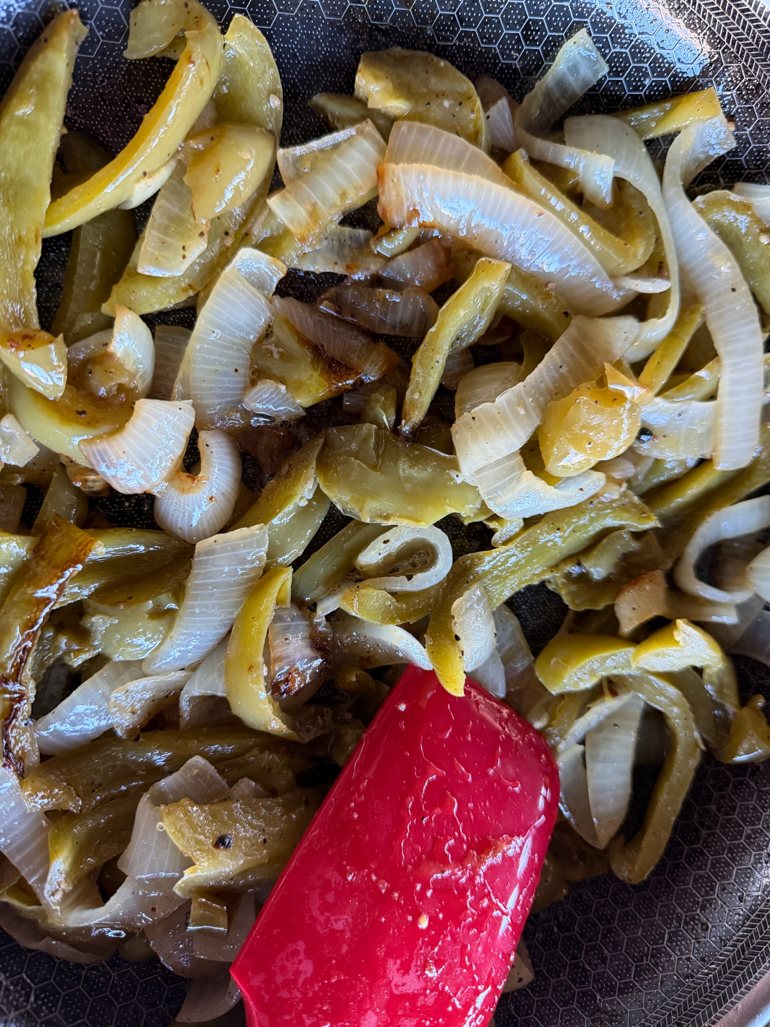 A close view of the softened green peppers and onions.
